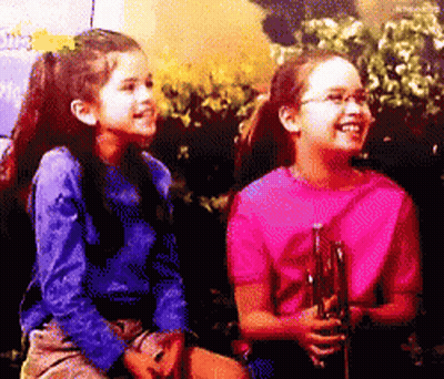 Two Young Girls Are Sitting Next To Each Other And One Is Wearing A Pink Shirt GIF