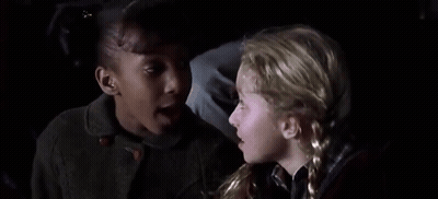 Two Young Girls Sitting Next To Each Other In Dark Room GIF