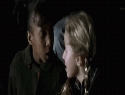 Two Young Girls Sitting Next To Each Other In Dark Room GIF