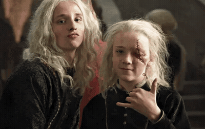 Two Young Girls With Blonde Hair Are Standing Next To Each Other . One Of The Girls Has A Scar On Her Face . GIF