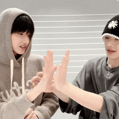 Two Young Men Are Giving Each Other A High Five While Wearing Hats . GIF