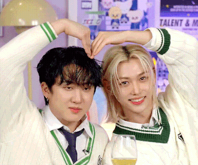 Two Young Men Are Making A Heart Shape With Their Hands In Front Of A Poster That Says Talent GIF