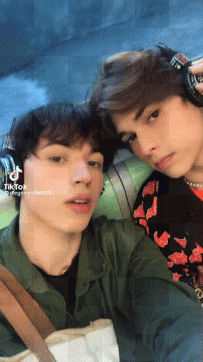 Two Young Men Are Posing For A Picture And One Of Them Has Tiktok Written On His Phone GIF