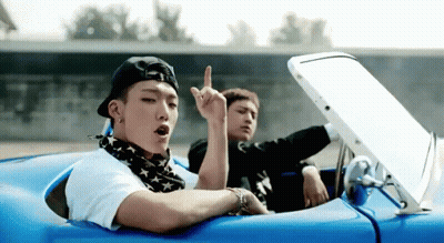 Two Young Men Are Sitting In A Blue Convertible Car And One Of Them Is Giving The Middle Finger GIF