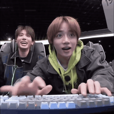 Two Young Men Are Sitting In A Roller Coaster And Playing A Video Game On A Keyboard . GIF