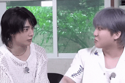 Two Young Men Are Sitting Next To Each Other And Looking At Each Other In Front Of A Window . GIF