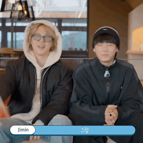 Two Young Men Are Sitting Next To Each Other And One Of Them Has The Name Jimin On The Bottom GIF