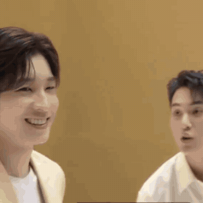 Two Young Men Are Sitting Next To Each Other And Smiling At Each Other . GIF