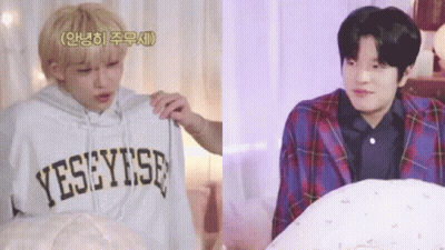 Two Young Men Are Sitting Next To Each Other In A Bedroom . One Of The Men Is Holding A Hoodie . GIF