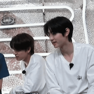 Two Young Men Are Sitting Next To Each Other In A Room . GIF
