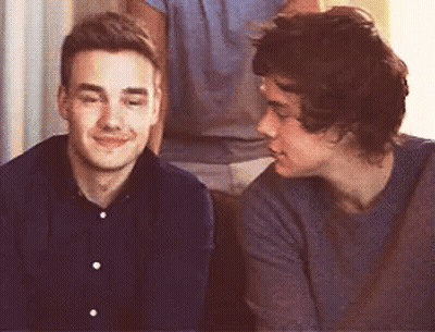 Two Young Men Are Sitting Next To Each Other On A Couch And Looking At Each Other . GIF