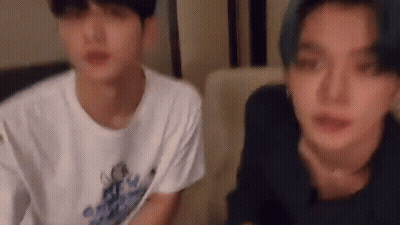 Two Young Men Are Sitting Next To Each Other On A Couch And Looking At Each Other . GIF
