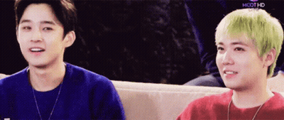 Two Young Men Are Sitting Next To Each Other On A Couch And One Has Green Hair GIF