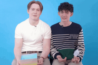 Two Young Men Are Sitting Next To Each Other With One Wearing A Sweater That Says Jw On It GIF