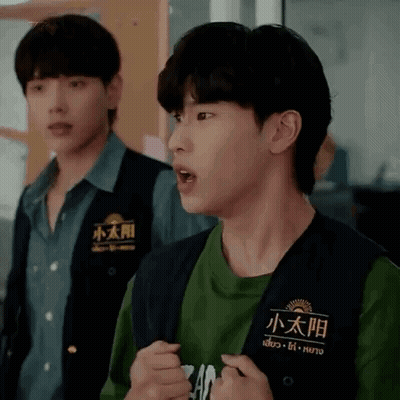 Two Young Men Are Standing Next To Each Other And One Is Wearing A Vest With Chinese Writing On It . GIF