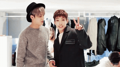 Two Young Men Are Standing Next To Each Other And One Of Them Is Giving A Peace Sign GIF