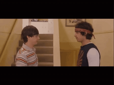 Two Young Men Are Standing Next To Each Other In A Hallway GIF
