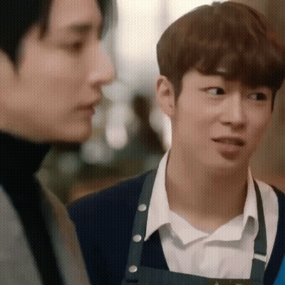 Two Young Men Are Standing Next To Each Other In A Restaurant . GIF