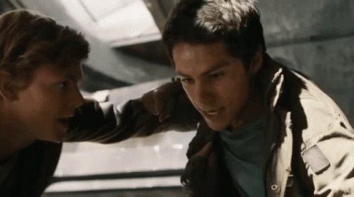 Two Young Men Are Standing Next To Each Other In A Room And Looking At Each Other . GIF