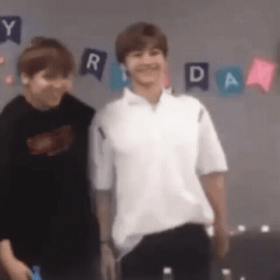 Two Young Men Are Standing Next To Each Other In A Room . One Of The Men Is Wearing A White Shirt . GIF