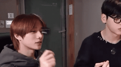Two Young Men Are Standing Next To Each Other In A Room . GIF