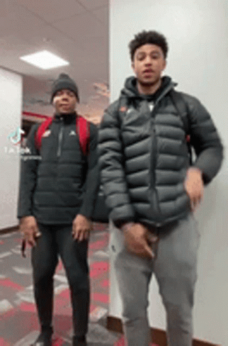 Two Young Men Are Standing Next To Each Other In A Room . GIF