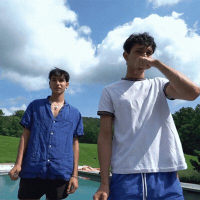 Two Young Men Are Standing Next To Each Other Near A Pool GIF