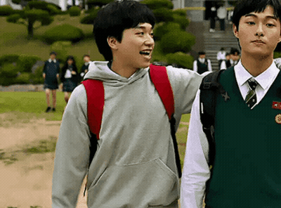 Two Young Men Are Standing Next To Each Other On A Sidewalk . GIF