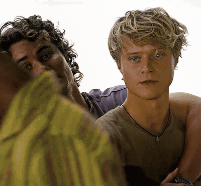 Two Young Men Are Standing Next To Each Other On A White Background . One Of The Men Has A Necklace Around His Neck . GIF
