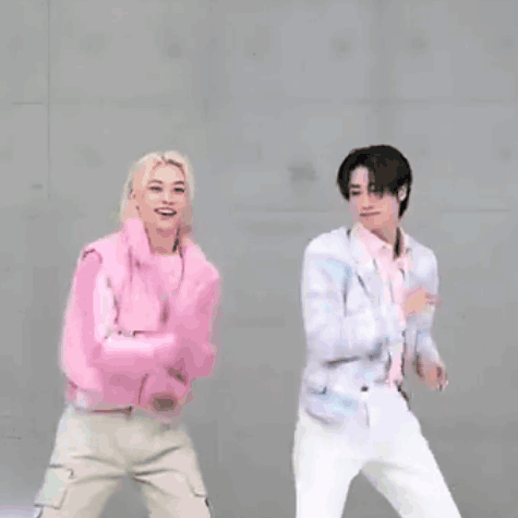 Two Young Men Are Standing Next To Each Other With Their Arms In The Air . GIF