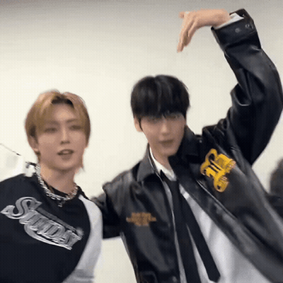 Two Young Men Are Standing Next To Each Other With Their Arms Outstretched . GIF