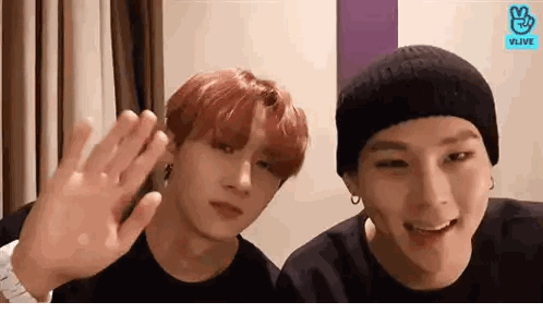 Two Young Men Are Waving At The Camera And One Of Them Is Wearing A Watch Sticker