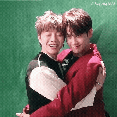 Two Young Men Hugging Each Other With A Green Background GIF