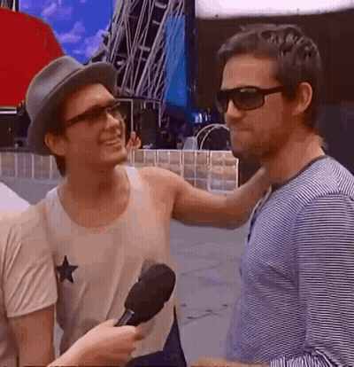 Two Young Men In Front Of We Are Champions Sign GIF
