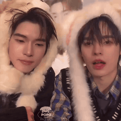 Two Young Men In Furry Hats Looking At Camera GIF