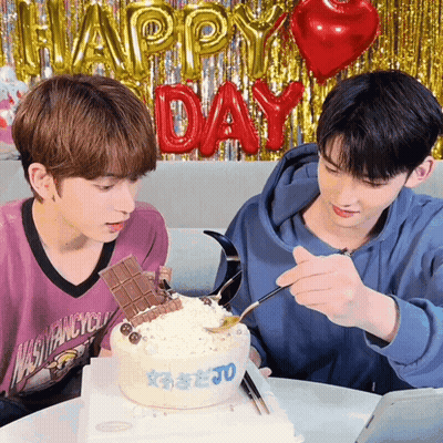 Two Young Men Looking At Cake With Happy Day Balloons GIF