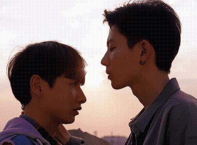 Two Young Men Looking At Each Other One With Earrings GIF