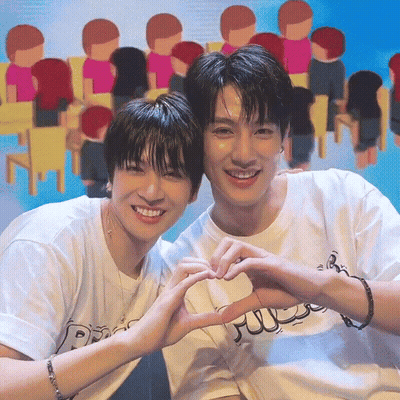 Two Young Men Making A Heart Shape With Their Hands In Front Of A Crowd GIF