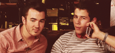 Two Young Men On Couch One On Phone GIF
