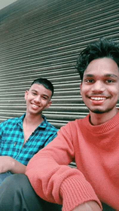 Two Young Men Posing For A Picture With One Wearing A Red Sweater GIF