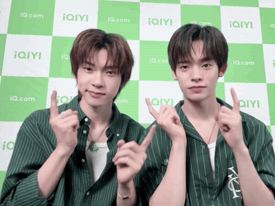 Two Young Men Posing In Front Of IQ.com Checkered Background GIF