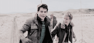 Two Young Men Running In Desert Holding Hands GIF