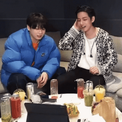 Two Young Men Sitting At Table With Drinks And Laptop GIF