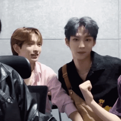 Two Young Men Sitting Next To Each Other One In Pink Shirt GIF
