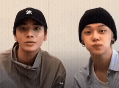 Two Young Men Sitting Next To Each Other Wearing Hats GIF