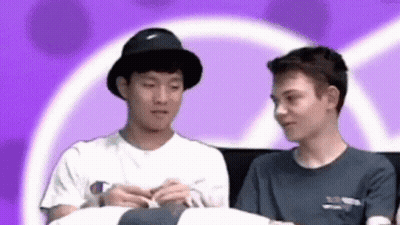 Two Young Men Sitting On Couch Looking At Each Other GIF