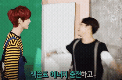Two Young Men Standing In Front Of Green And White Wall One Red Hair One Blonde GIF