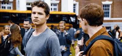 Two Young Men Standing In Front Of School Bus Talking GIF