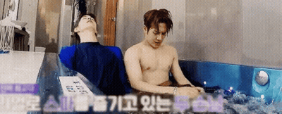 Two Young Men Standing Next To Each Other In Front Of Green And White Wall Red Hair And Black Hair GIF