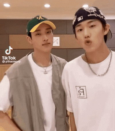 Two Young Men Standing Next To Each Other Wearing Hats And Shirts GIF